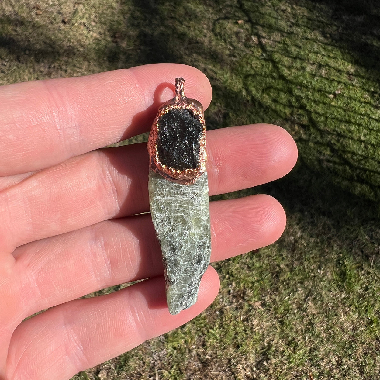 "Handcrafted copper electroformed pendant featuring Agni Manitite and Green Kyanite crystals, designed for esoteric and spiritual purposes. Unique, artisanal jewelry combining the grounding energy of Agni Manitite with the healing properties of Green Kyanite, perfect for those seeking balance and inner peace."